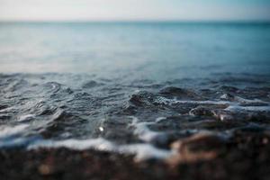 Sea waves of the blue sea with foam roll ashore the golden shore. Close-up photo