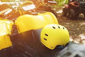 Yellow helmet on an ATV in the forest, in the mud. Wheels and elements of all-terrain vehicles in mud and clay. Active leisure, sports and tourism photo