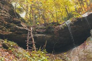 An old staircase leading up to the waterfall in the autumn forest. photo