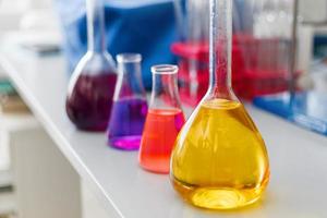 matraz de laboratorio químico con soporte líquido azul púrpura-rosa sobre la mesa foto