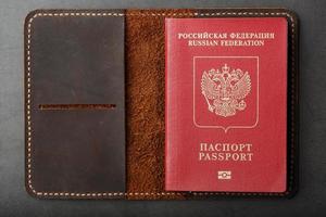 cubierta de cuero marrón con un pasaporte rojo sobre un fondo oscuro foto