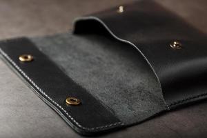 Black wallet made of genuine leather on a dark background. Handmade leather items photo