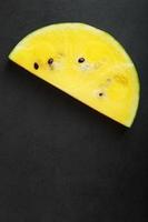 Juicy slice of yellow watermelon on a stone black background. Conceptual colors of summer. Top view as a background or substrate photo