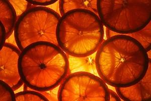 Juicy slices of ripe orange with backlight in the form of cut rings, textural background-substrate photo