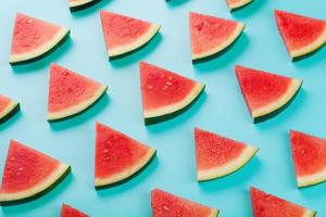 Pattern of slices of fresh slices of red and yellow watermelon on a blue background. Top view photo