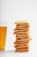 A stack of golden wheat cookies and a mug of fragrant green tea in on a white background. Cookies laid out in a breakfast column and a golden highlight with tea mugs photo