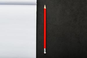 Notepad with a red pencil on a black stone plate background, for education, recording goals and deeds photo