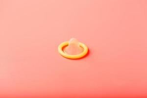 Opened condom on a pink background, close-up, top view. photo