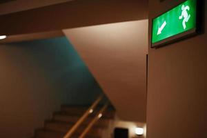 Green escape route sign on a flight of stairs. photo