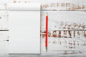 Notepad with a red pencil on a white wooden table against the background, for education, recording goals and deeds photo