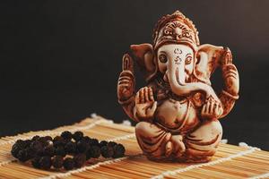 Hindu god Ganesh on a black background. Statue with incense smoke aromo sticks photo