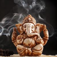 Hindu god Ganesh on a black background. Statue with incense smoke aromo sticks photo