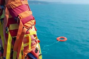 The orange-colored lifebuoy is thrown into the blue sea against the background of the life-rescue photo