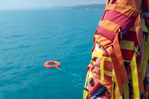 The orange-colored lifebuoy is thrown into the blue sea against the background of the life-rescue photo