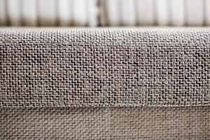 Closeup of a fragment of a beige textile sofa in the room. Texture of expensive fabric on furniture photo