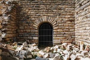 The door is from the metal grille of an ancient antique building, a castle of stone with sprawling blocks. photo