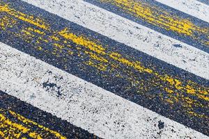 Pedestrian crossing, yellow and white stripes on wet asphalt in the form of texture and substrate photo