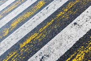 cruce de peatones, rayas amarillas y blancas sobre asfalto húmedo en forma de textura y sustrato foto