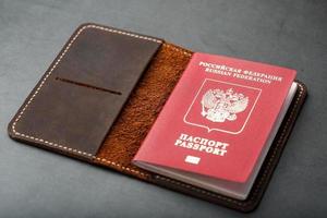 cubierta de cuero marrón con un pasaporte rojo sobre un fondo oscuro foto