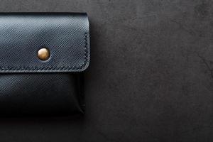 billetera negra hecha de cuero genuino sobre un fondo oscuro. artículos de cuero hechos a mano foto
