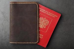 Brown leather cover with a red passport on a dark background photo