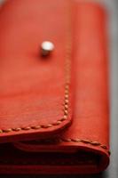 Purse made of genuine red leather, handmade on a dark background. Stitched seams. photo