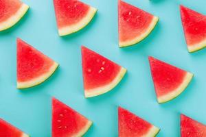 Pattern of slices of fresh slices of red and yellow watermelon on a blue background. Top view photo