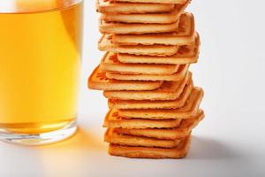 A stack of golden wheat cookies and a mug of fragrant green tea in on a white background. Cookies laid out in a breakfast column and a golden highlight with tea mugs photo