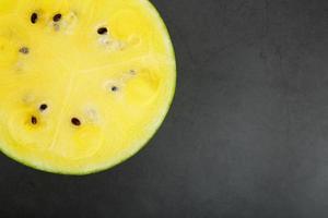 Half of tasty and ripe yellow watermelon on a black background, texture of juicy pulp of ripe yellow watermelon with seeds photo