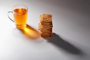 A stack of golden wheat cookies and a mug of fragrant green tea in on a gray background. Cookies laid out in a breakfast column and a golden highlight with tea mugs photo