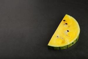 Juicy slice of yellow watermelon on a stone black background. Conceptual colors of summer. Top view as a background or substrate photo