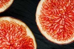 Figs are ripe. Closeup of sliced fig fruits in the form of a texture inscribed in a rectangle on a black texture background photo