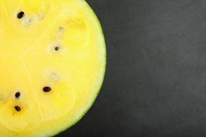 Half yellow watermelon on a black background, texture of juicy pulp of ripe yellow watermelon photo