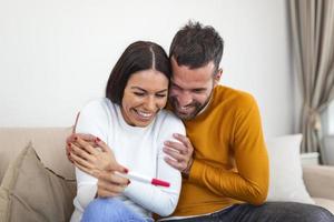 Shot of a couple feeling happy after taking a home pregnancy test. I'm pregnant Happy young couple with pregnancy test. Joyful couple with positive pregnancy shown in the test device photo