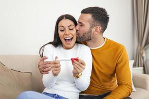 feliz pareja joven haciéndose una prueba de embarazo en casa. nos convertimos en padres. pareja joven que se siente feliz después de hacerse una prueba de embarazo en casa foto