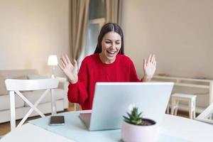 Young woman waving at laptop and talking to her friends via video call, girl student talking by video conference call, female teacher trainer tutoring by webcam, online training, e-coaching concept photo