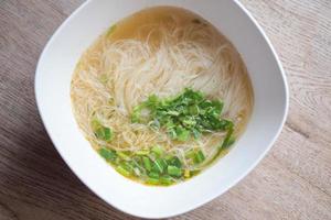 Rice vermicelli noodles bowl - rice noodles soup bowl with coriander on wooden background photo