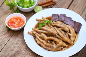 sopa de patas de pollo guisada, cocinando estofado de patas de pollo en blanco con ingredientes de hierbas y especias con vegetales de limón picante sobre fondo de madera, menú de comida china asiática estofado - comida tailandesa foto