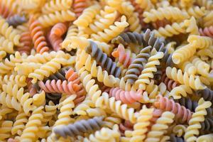 Pasta raw macaroni background, close up raw macaroni spiral pasta uncooked delicious whole grain fusilli pasta for cooking food - top view photo