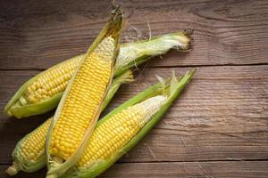 Corn on the cob, sweet corn for cooking food, fresh corn on wooden background, harvest ripe corn organic - top view photo