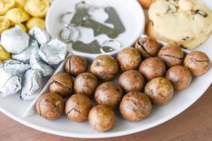 Galletas de chocolate con nueces de macadamia - juego de envases de nueces de macadamia en placa de bandeja natural alta en proteínas foto