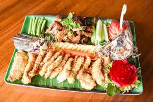 Lubina filete de pescado comida cocida estilo tailandés asiático - ensalada de lubina pescado frito crujiente decorado en un plato servido en una mesa de madera comida cena foto