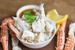Crab meat - Cooked crab claws and legs on white bowl and seafood sauce on the table , blue swimming crab photo