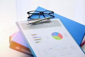 Business graph chart report paper financial document and file with  pen and glasses on desk photo