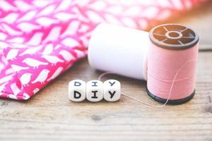 diy thread and needle on wooden table - bobbins with thread and needles, striped fabric Old sewing tools on the old wooden background photo