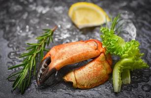 Seafood frozen boiled crab claws - Fresh crab with ingredients lemon rosemary on ice at market photo