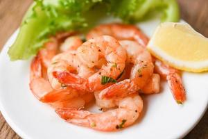 Appetizing cooked shrimps baked prawns , Seafood shelfish - Shrimp grilled delicious seasoning spices on white plate wooden background photo