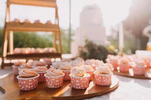 Gourmet cupcakes with white buttercream frosting and sprinkles on wooden background photo