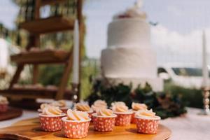 pastelitos gourmet con glaseado de crema de mantequilla blanca y chispas sobre fondo de madera foto