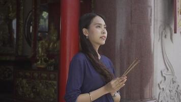 een aantrekkelijk meisje bidden Bij een Chinese altaar in Bangkok, Thailand. video